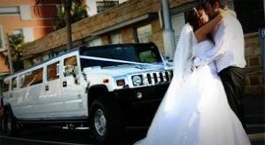 Image bride and groom hugging and kissing in front of a white New Haven H2 Hummer