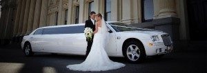 Image of bride and groom in front of white Norwalk wedding limousine
