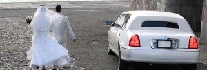 Image of bride and groom at the beach next to a white Lincoln Town Car